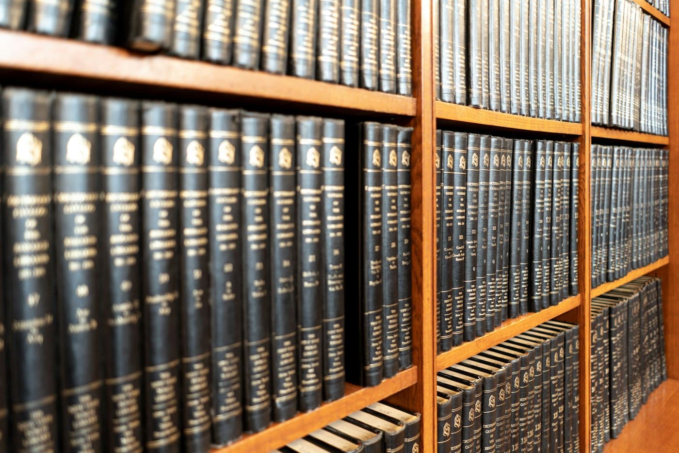 Estante de madeira com uma coleção de livros de encadernação escura